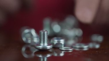 Yaşlı erkek parmakları gümüş metal vidayı alır ve tahta masadan fırlar.