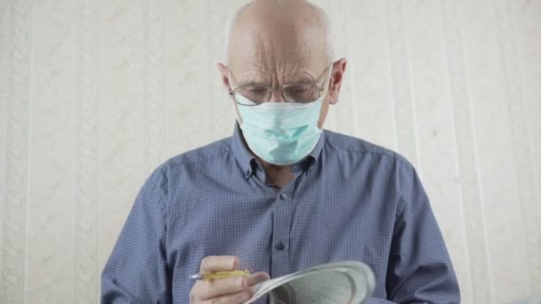 Homem adulto vestindo óculos e máscara facial lendo jornal — Vídeo de Stock