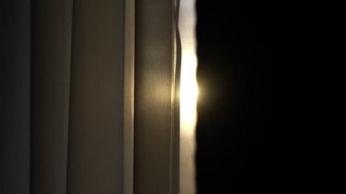 Parlak güneş ışığı büyük pencerelerde asılı tekstil perdelerinde parlıyor.