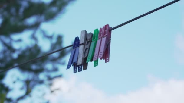 Pinzas de ropa multicolores colgando en el tendedero en el patio trasero al aire libre. — Vídeo de stock