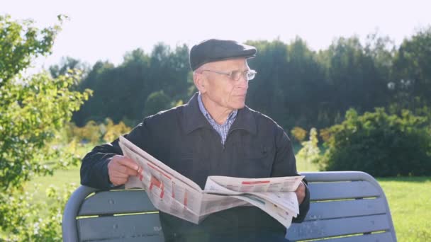 Pensionar în capac și ochelari citește ziare mari — Videoclip de stoc