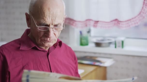 Rentner mit grauen Haaren liest Blatt Zeitung — Stockvideo