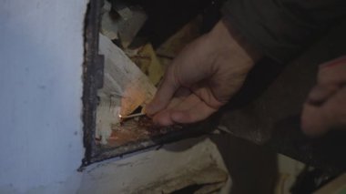 Titreyen yaşlı insan el yanıkları kibrit çakar ve ocağa koyar.
