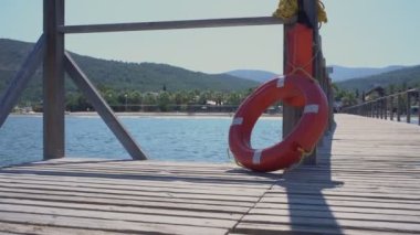 Parlak kırmızı can simidi oteldeki iskele ahşap çitine asılı.