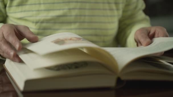 Aged man in yellow striped pullover hands turn book pages — Stock Video