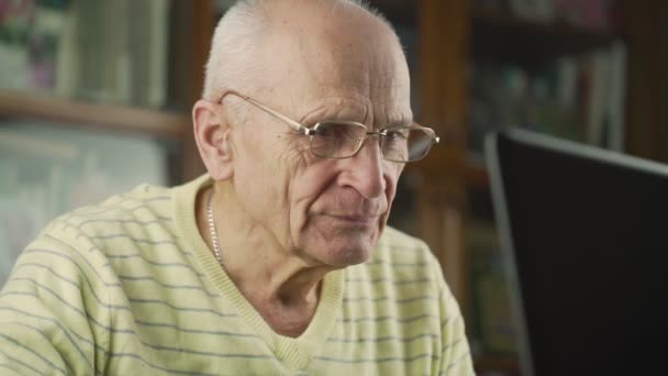 Rentner mit Brille blickt in schwarzen Laptop — Stockvideo