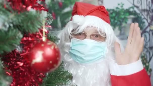 Αστείος Άγιος Βασίλης με λευκή γενειάδα που φοράει μάσκα προσώπου και κόκκινο καπέλο — Αρχείο Βίντεο