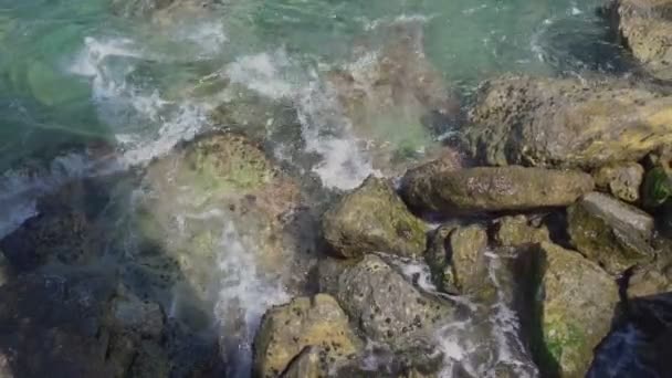 Modré mořské vlny s malou bílou pěnou mezi mokrými hnědými skálami — Stock video