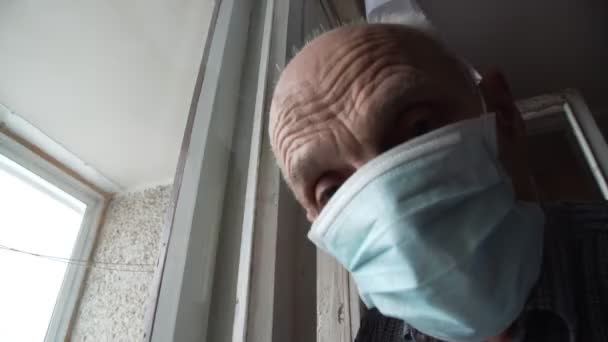 Senior man met gezichtsmasker kijkt recht en draait hoofd — Stockvideo