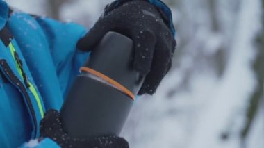 Eldivenli kıdemli adam termos açar sıcak çay ve içecek koyar.