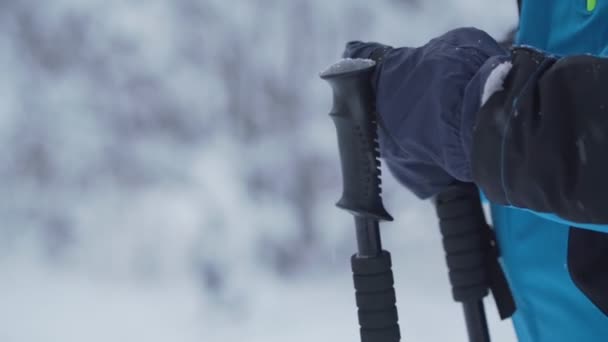Persoon skiër in warme jas en handschoenen neemt zwarte palen — Stockvideo