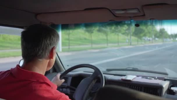 Minivan hombre conductor en la calle de la ciudad en la vista del día de verano por detrás — Vídeo de stock