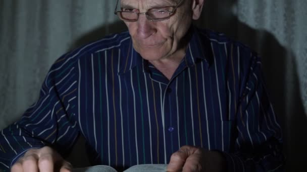 Ανώτερος άνθρωπος συνταξιούχος γυαλιά διαβάζει λογοτεχνία μυθοπλασίας — Αρχείο Βίντεο