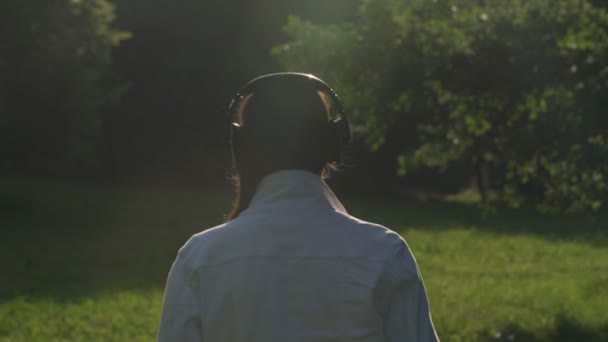 Lady caminha ao longo do parque e gosta de natureza ouvir música — Vídeo de Stock