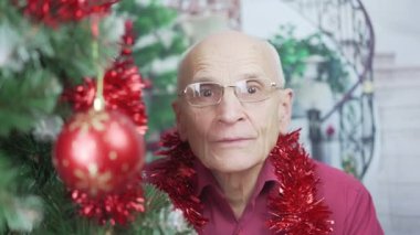 Gözlüklü yaşlı bir erkek görüntülü arama ile iletişim kuruyor.