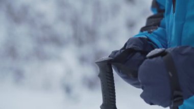 Sıcak eldivenli profesyonel kayakçı ellerinde siyah direkleri tamir ediyor.