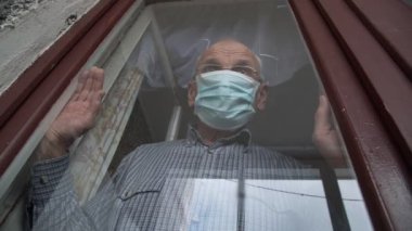 Tek kullanımlık maskeli yaşlı emekliler eski pencerelere yaslanıyor