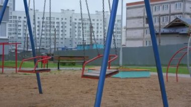 Zincirlerde birkaç kırmızı salıncak çocukların oyun alanında kayalar