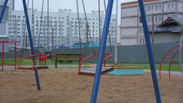 Paar mit roten Schaukeln auf Ketten schaukelt auf Kinderspielplatz — Stockvideo