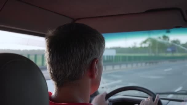 Hombre cansado con el pelo gris corto en jersey rojo conduce a casa en la carretera — Vídeos de Stock