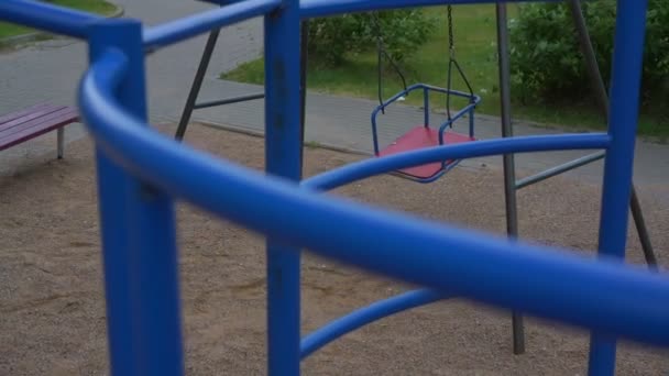赤と青のスイングは茂みの子供たちの遊び場で動きます — ストック動画