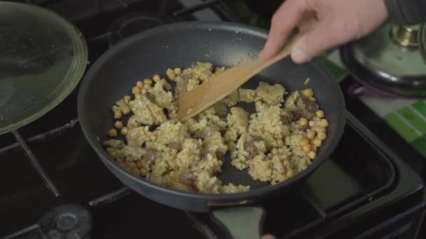 Человек смешивает кашу на сковороде и покрывает крышкой — стоковое видео