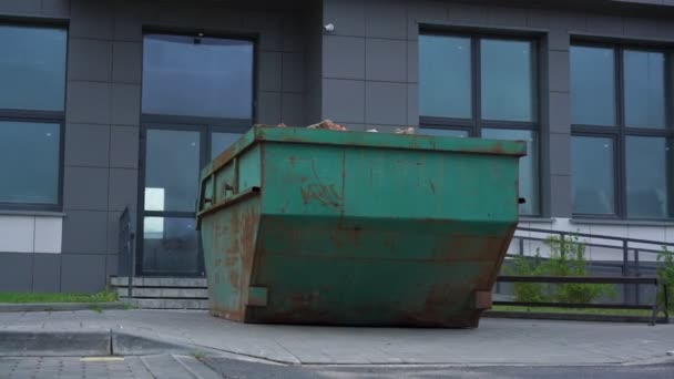 Зелений іржавий металевий контейнер зі сміттям у будівлі подвір'я — стокове відео