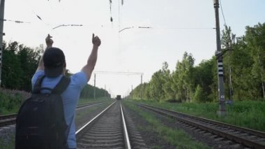 Sırt çantalı adam trene yetişemedi ve raylara oturdu.