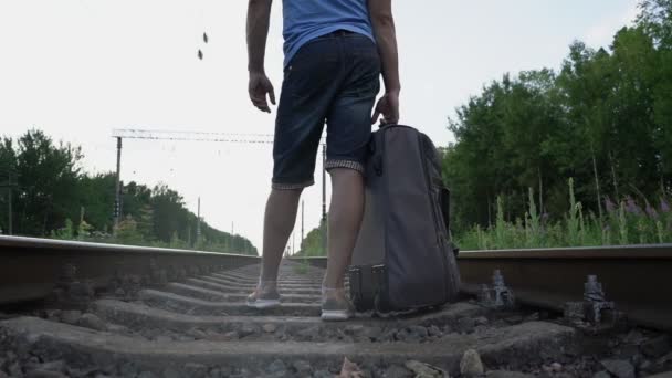 Mężczyzna w krótkich spodenkach z torbą drogową stojącą na szynie widok z tyłu — Wideo stockowe