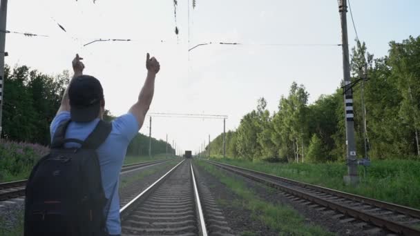 Muž s batohem nemohl dohnat vlak a sedí na kolejích — Stock video