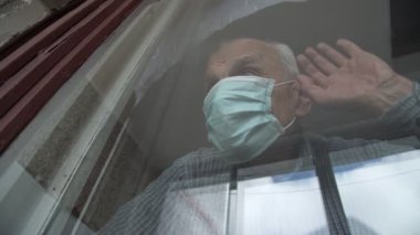 Duygusal kıdemli emekli yüzlü adam ellerini pencereye koydu.