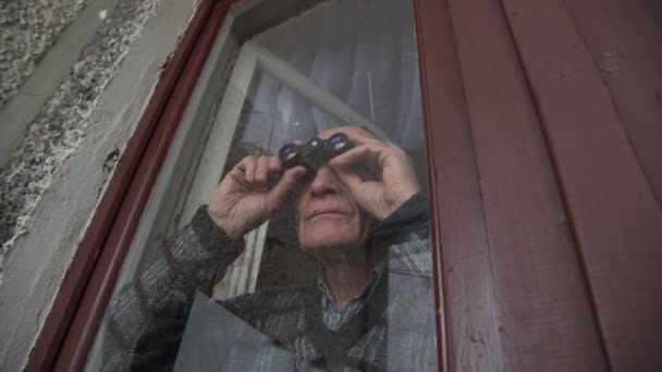 Koncentrerad senior pensionär man innehar svart kikare — Stockvideo