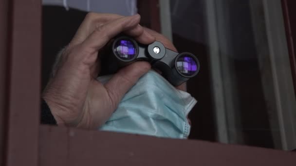 Homem sênior em espiões descartáveis máscara facial com binóculos — Vídeo de Stock