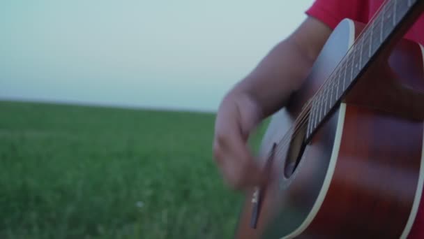 Hombre toca en cuerdas de guitarra acústica durante el día — Vídeo de stock