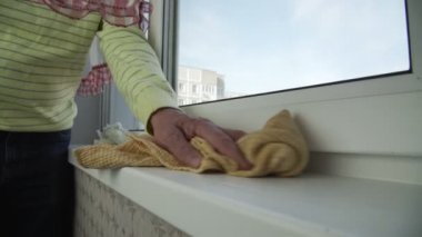 Kazaktaki yaşlı adam pencere kenarındaki tozu siliyor.