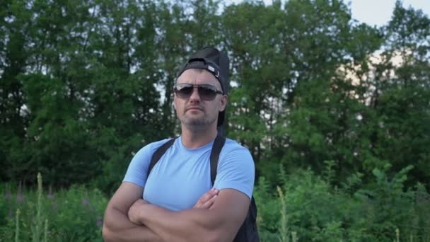 Velkolepý muž v slunečních brýlích s kytarou stojí na přírodě v létě — Stock video