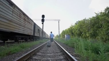 Trenin yanından geçen ve bavulu çeken bir adam var.