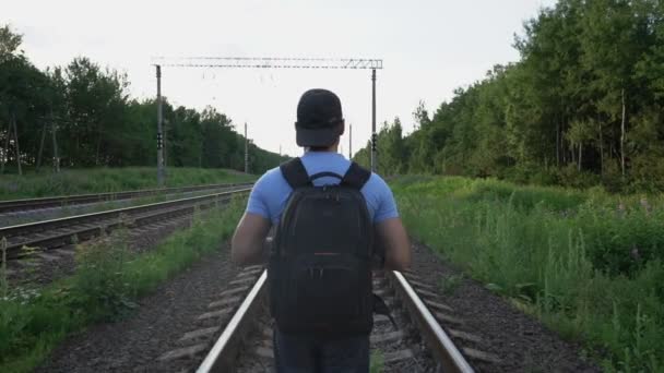 Людина з рюкзаком повільно ходить по залізниці — стокове відео