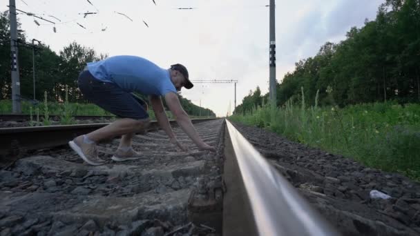 Uomo si avvicina alla ferrovia mette la testa sulle rotaie e in attesa di treno — Video Stock