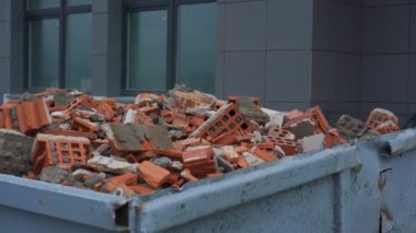 İnşaata karşı metal konteynerin içinde turuncu tuğla yığını