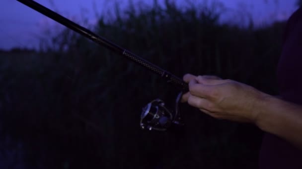 Ψαράς βάζει δόλωμα στο αγκίστρι αλιείας και ρίχνει καλάμι αλιείας στο νερό το βράδυ — Αρχείο Βίντεο
