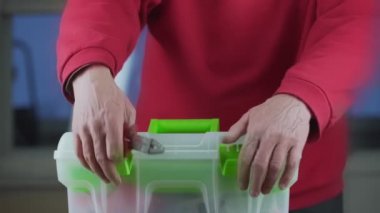 Eski servis çalışanı elleri, penseyi yeşil beyaz alet çantasına koyar.