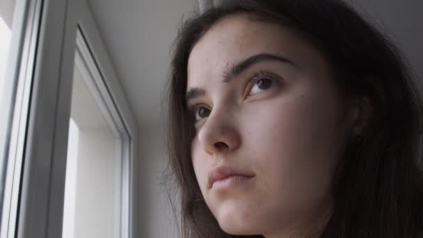 Melancholická brunetka dívka se smutkem dívá oknem — Stock video