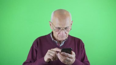 Gözlüklü yaşlı adam akıllı telefon kullanıyor.