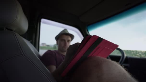 Man sitting in car and working on tablet holding him on his knee — Stock Video