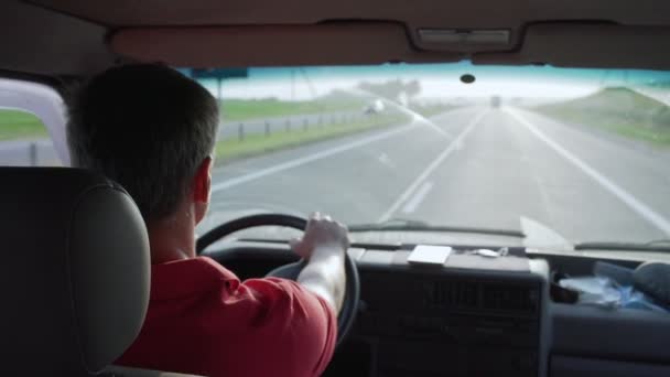 赤いシャツの男がミニバンに乗って道路をよく見て — ストック動画