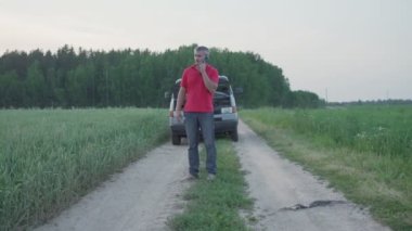 Kırık minivan vagonunun yanında duran adam ne yazık ki telefonla konuşuyor.