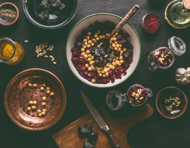 Sağlıklı vejetaryen pancar salatası hazırlama bezelye ve çam fıstığı ile koyu mutfak masası arka planında malzemelerle, üst manzara. Mor sebzeler yiyor. Temiz diyet yemekleri..