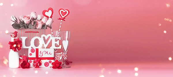情人节礼物礼品盒 玫瑰束 购物袋里的红心 带着彩带 站在红色粉红的背景上 带着酒壶 爱的宣言横幅 — 图库照片