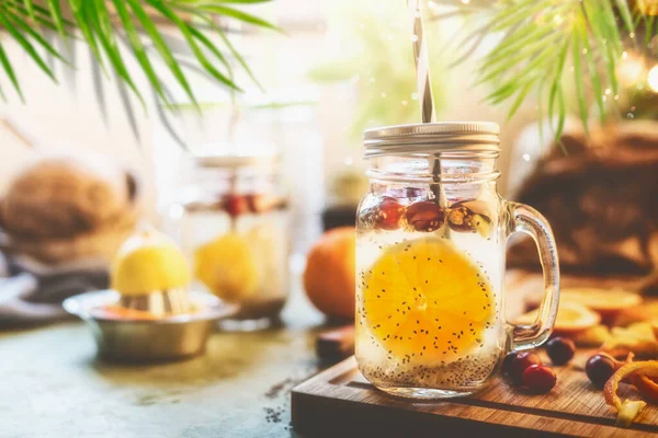 中国の種子と健康的な夏の飲み物は水をデトックス オレンジフルーツスライス レモン汁と材料とキッチンテーブルの上にマソン瓶のクランベリー フィットネスドリンクコンセプト ストックフォト